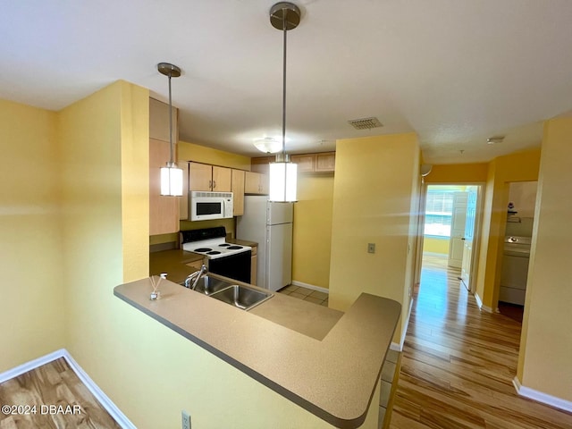 kitchen with kitchen peninsula, light brown cabinetry, hanging light fixtures, white appliances, and light hardwood / wood-style flooring