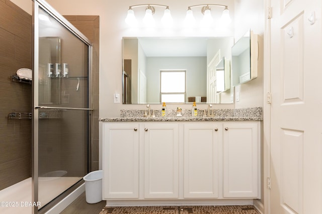 full bathroom featuring a sink, a stall shower, and double vanity