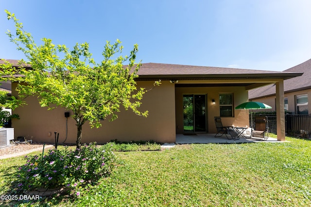 back of property with a yard, fence, stucco siding, and a patio area