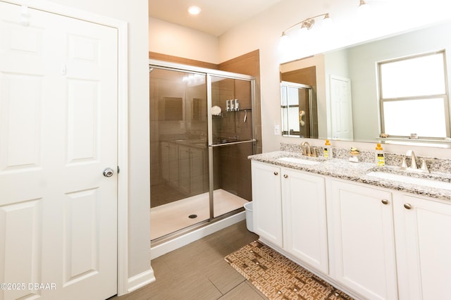 full bathroom with double vanity, a stall shower, and a sink