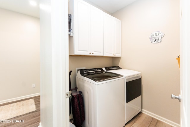 washroom with washing machine and clothes dryer, cabinet space, light wood-style flooring, and baseboards