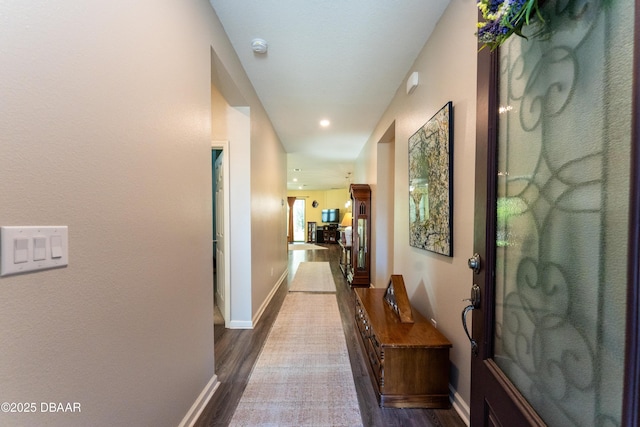 hallway featuring dark wood-type flooring, recessed lighting, and baseboards