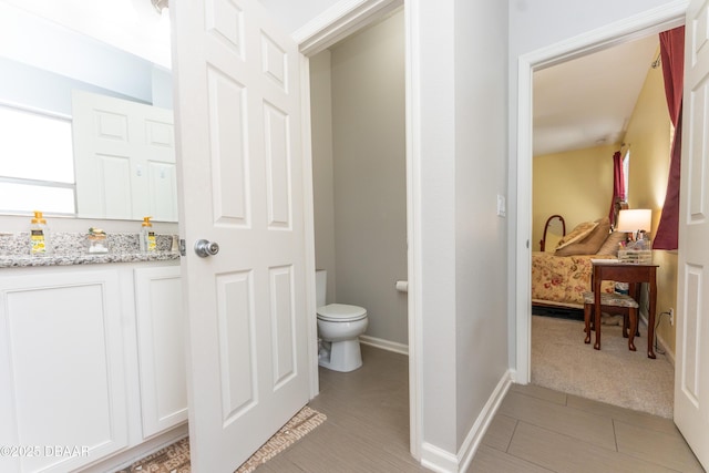 bathroom featuring ensuite bath, toilet, and baseboards