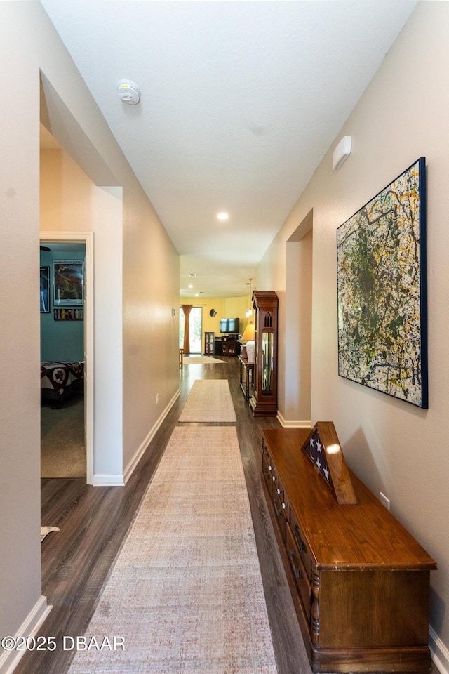 hallway featuring dark wood-type flooring and baseboards