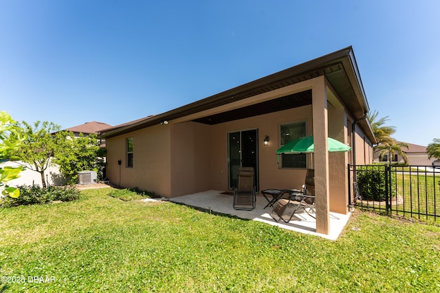 rear view of house with stucco siding, a patio, a yard, and fence