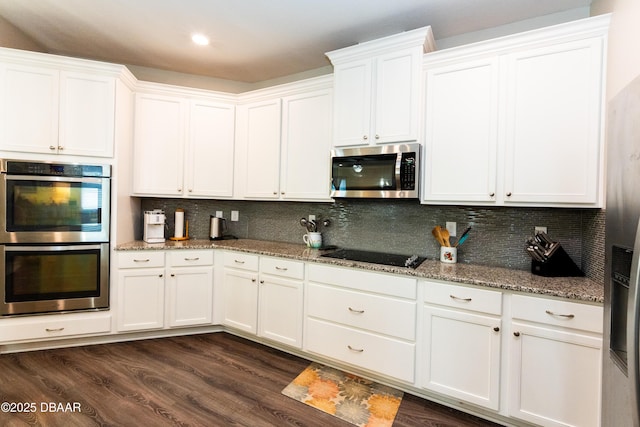 kitchen with light stone counters, dark wood-style floors, stainless steel appliances, white cabinets, and tasteful backsplash