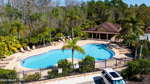 community pool with a patio and fence