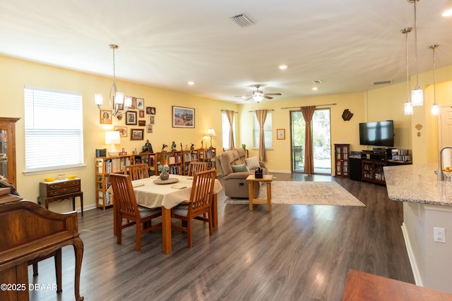 dining area featuring ceiling fan with notable chandelier, visible vents, and dark wood-style flooring