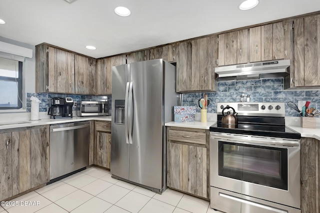 kitchen featuring backsplash, light tile patterned floors, and appliances with stainless steel finishes