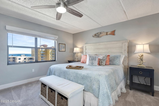 carpeted bedroom featuring ceiling fan and a textured ceiling