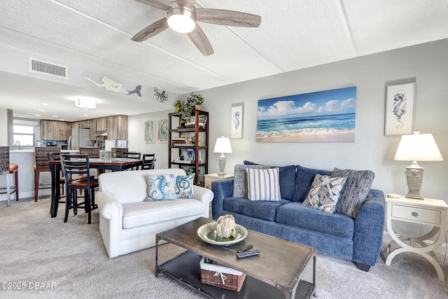 carpeted living room featuring sink, a textured ceiling, and ceiling fan