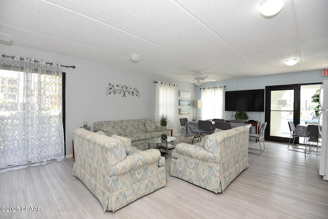 living room featuring hardwood / wood-style flooring, ceiling fan, and a textured ceiling