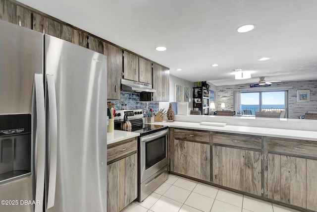 kitchen featuring appliances with stainless steel finishes, tasteful backsplash, light tile patterned floors, ceiling fan, and kitchen peninsula