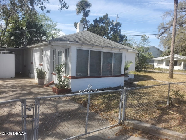 view of property exterior featuring roof with shingles, a fenced front yard, and a gate