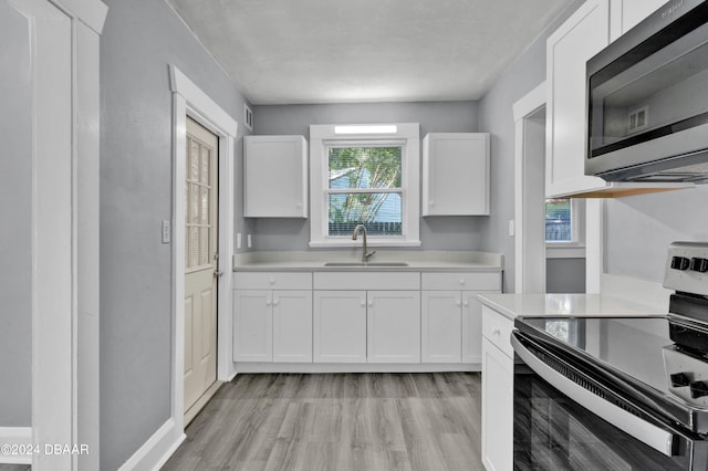 kitchen featuring white cabinets, sink, and electric range