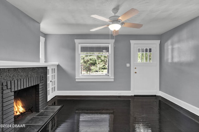 unfurnished living room featuring dark wood-type flooring, ceiling fan, and a fireplace