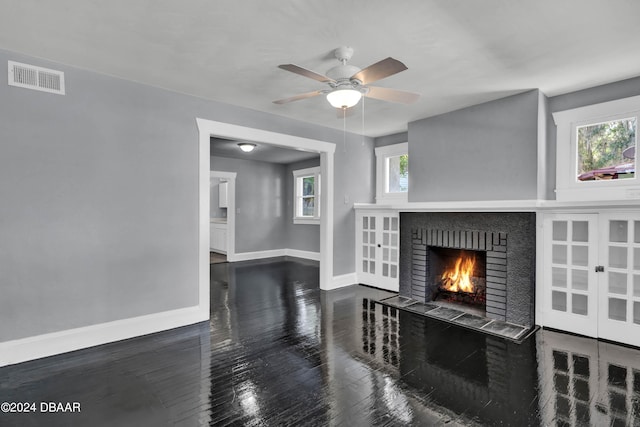 living room featuring a brick fireplace, plenty of natural light, and dark wood-type flooring