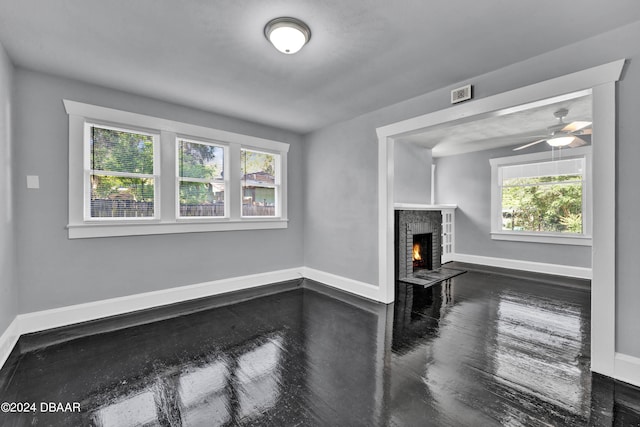 living room with a brick fireplace, ceiling fan, a healthy amount of sunlight, and dark hardwood / wood-style flooring