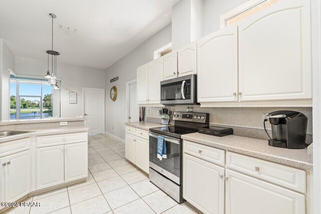 kitchen with light tile patterned flooring, white cabinetry, backsplash, appliances with stainless steel finishes, and decorative light fixtures