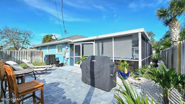 back of house with a patio area, a fenced backyard, and a sunroom