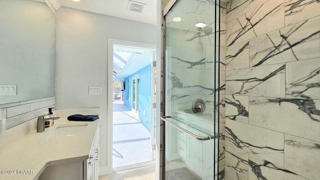 bathroom with a marble finish shower, visible vents, and vanity