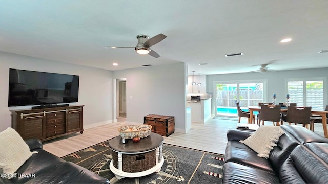 living area featuring ceiling fan, light wood finished floors, visible vents, and baseboards