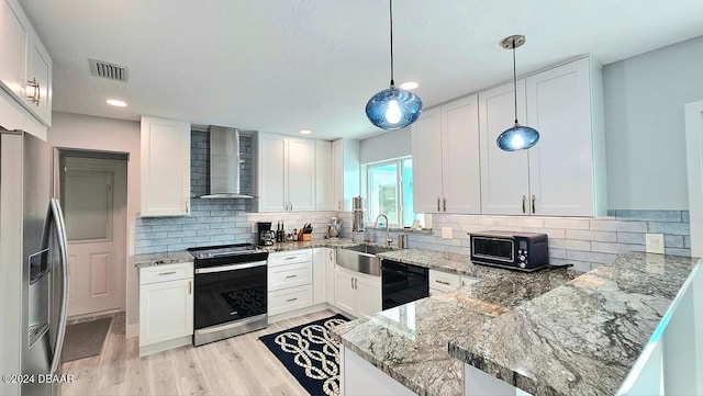 kitchen with white cabinets, wall chimney range hood, a peninsula, black appliances, and pendant lighting