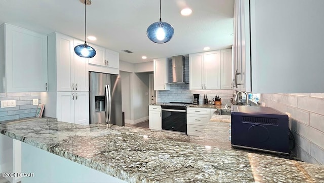 kitchen with stainless steel appliances, a peninsula, white cabinetry, hanging light fixtures, and wall chimney exhaust hood