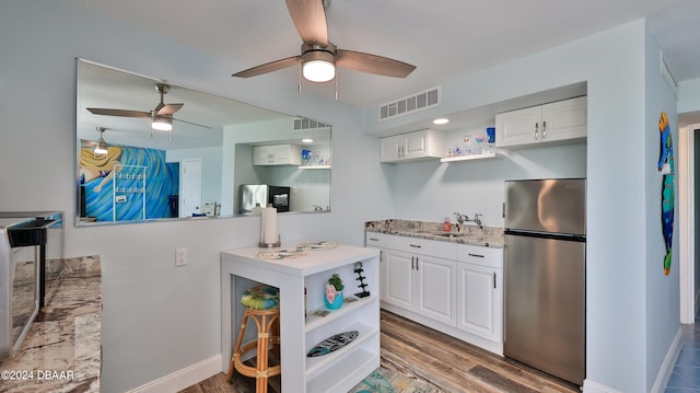 kitchen featuring sink, hardwood / wood-style floors, stainless steel fridge, and white cabinets