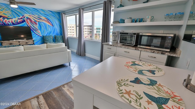 219 S Atlantic Ave Unit 440, Daytona Beach, FL 32118 - kitchen with stainless steel microwave, white cabinetry, open floor plan, open shelves, and wood finished floors