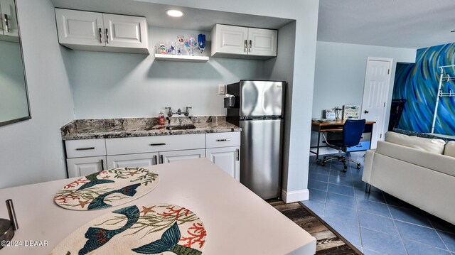 kitchen with white cabinetry, stone counters, stainless steel fridge, and dark hardwood / wood-style floors