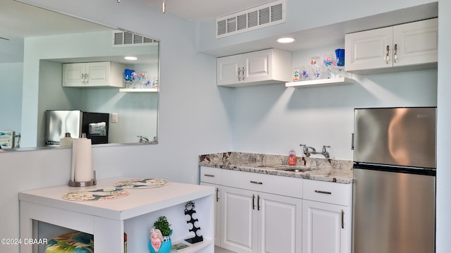 kitchen with stainless steel fridge and white cabinetry