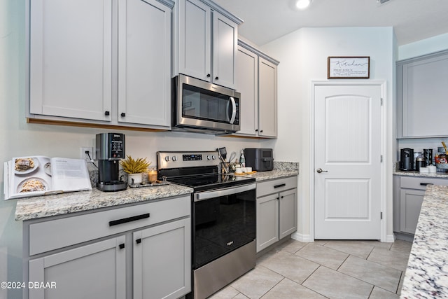 kitchen featuring appliances with stainless steel finishes, light stone counters, and light tile patterned floors