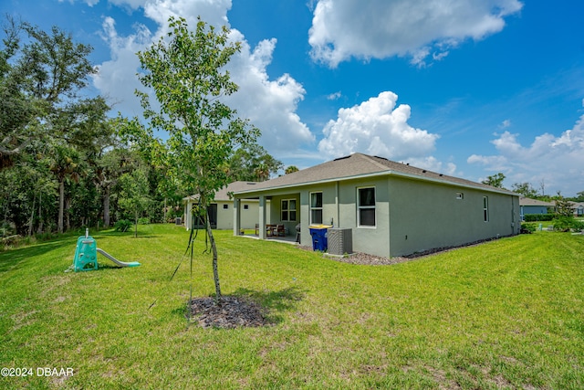 rear view of house featuring central AC, a lawn, and a patio