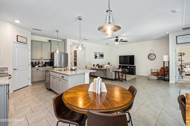 tiled dining space featuring a textured ceiling, sink, and ceiling fan