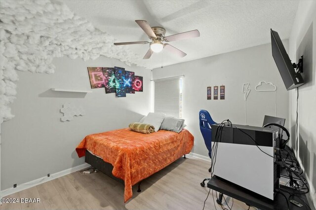 bedroom featuring light wood-type flooring, a textured ceiling, and ceiling fan