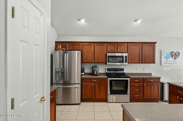 kitchen with light tile patterned floors, a textured ceiling, and appliances with stainless steel finishes