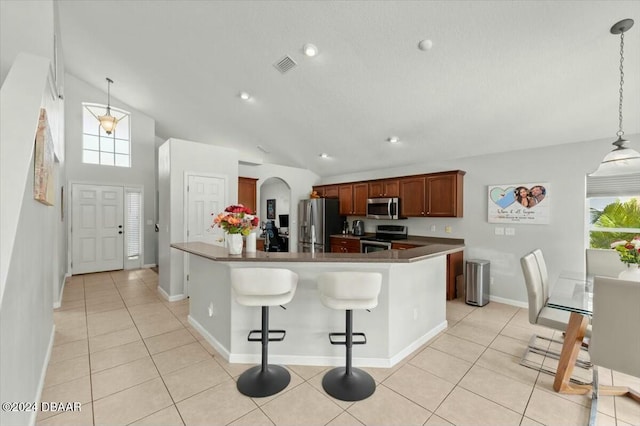 kitchen with light tile patterned floors, pendant lighting, lofted ceiling, and appliances with stainless steel finishes