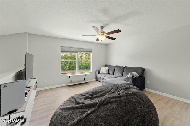 bedroom with ceiling fan, light hardwood / wood-style floors, and a textured ceiling