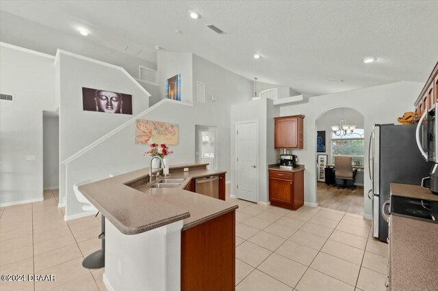 kitchen featuring high vaulted ceiling, sink, light tile patterned floors, a kitchen bar, and stainless steel appliances