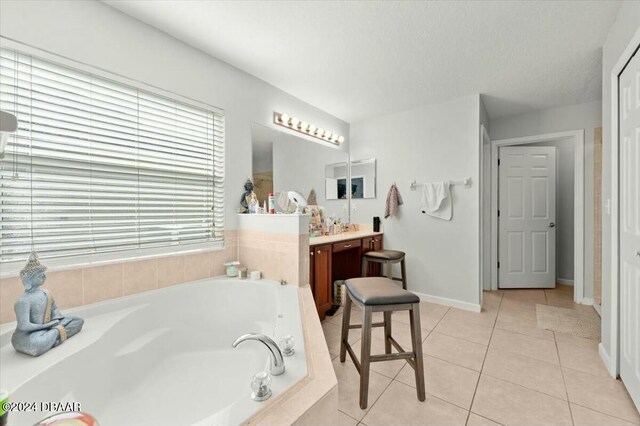 bathroom with vanity, tile patterned flooring, and a relaxing tiled tub