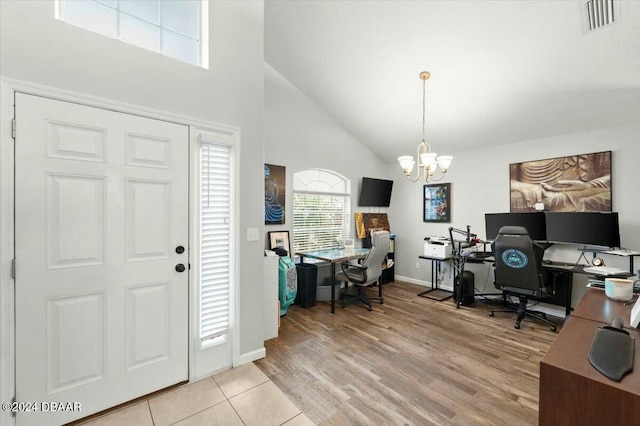 foyer featuring a chandelier, a towering ceiling, and light hardwood / wood-style flooring