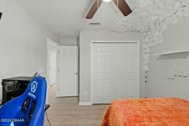 bedroom with ceiling fan, light wood-type flooring, and a closet