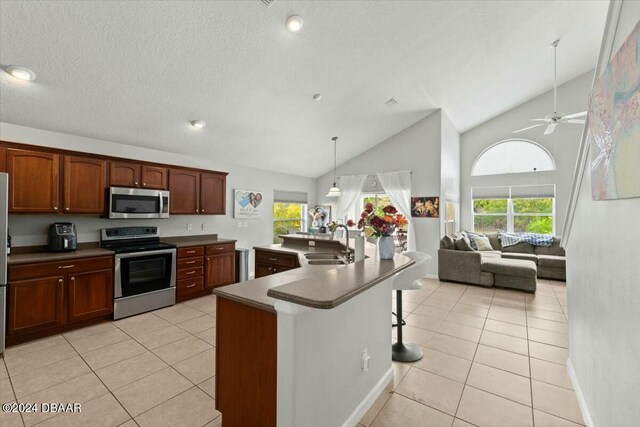 kitchen with appliances with stainless steel finishes, light tile patterned floors, ceiling fan, and sink