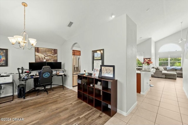 office space with ceiling fan with notable chandelier, light hardwood / wood-style floors, and vaulted ceiling