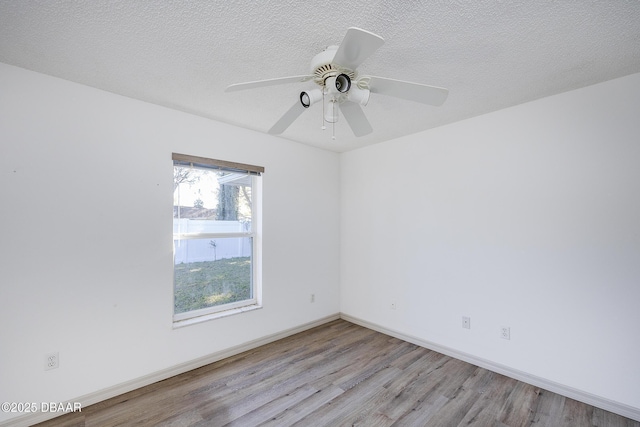 unfurnished room with ceiling fan, baseboards, a textured ceiling, and wood finished floors