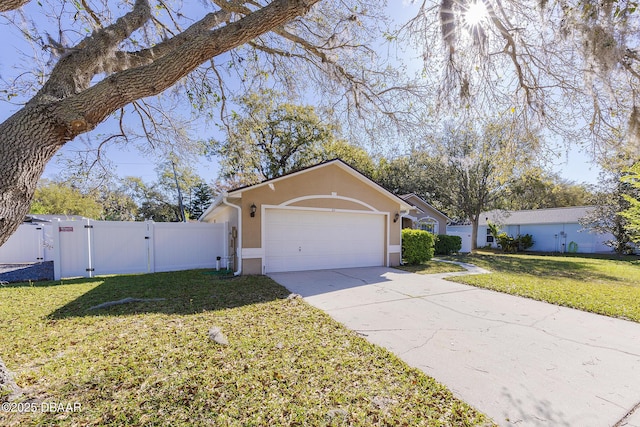 view of front facade featuring stucco siding, concrete driveway, a front yard, and a gate