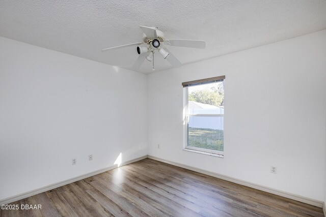 spare room featuring baseboards, a textured ceiling, a ceiling fan, and wood finished floors