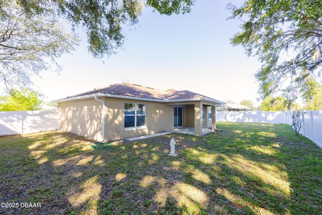 rear view of house with a patio, a fenced backyard, a lawn, and stucco siding