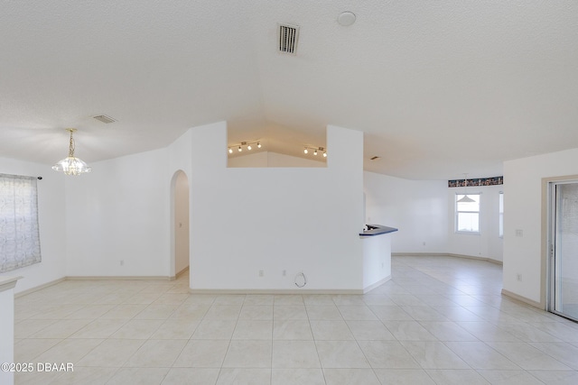 unfurnished room featuring arched walkways, visible vents, a textured ceiling, and an inviting chandelier